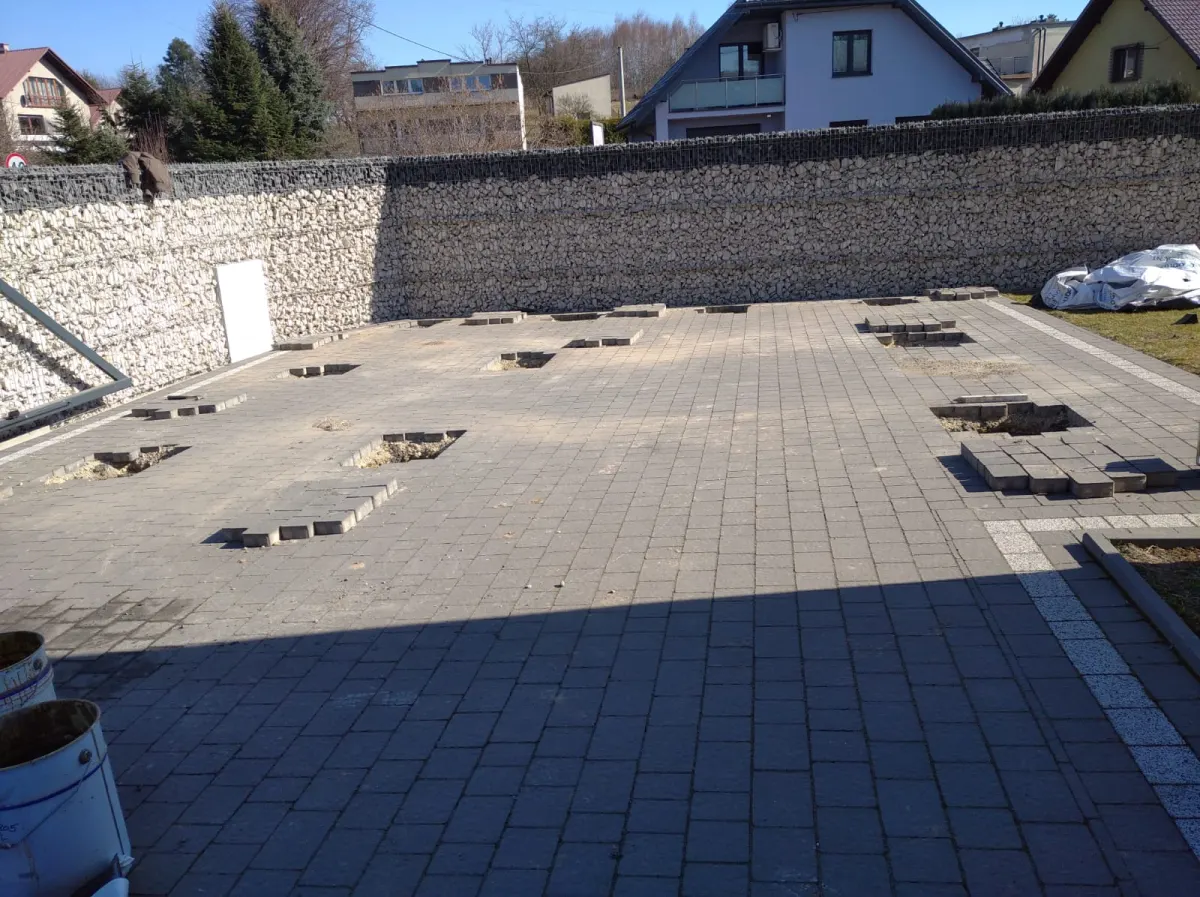 Gotowa nawierzchnia z kostki z wyjętymi fragmentami w miejscach słupków fundamentowych.